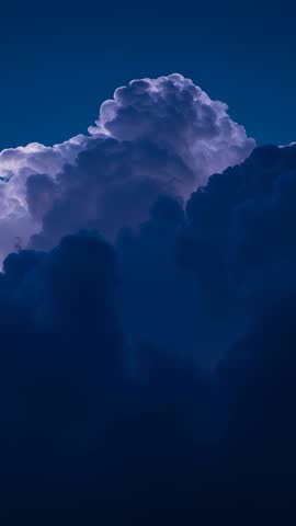 Vertical video capturing cumulonimbus cloud rising at twilight with rim lighting and thunderhead
