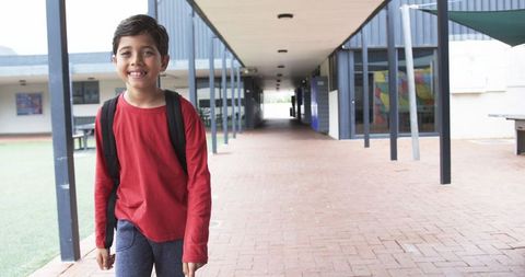 Happy Student in School Corridor with Backpack and Red Shirt