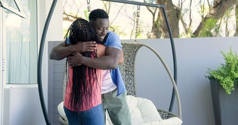 Happy couple embracing on modern patio with swing chair
