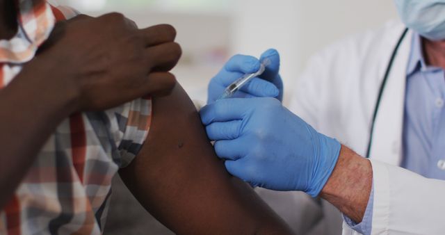 Doctor administering vaccination to patient's arm in clinical setting. Shows importance of healthcare and immunization. Use for medical, public health, vaccine promotion, and educational materials.