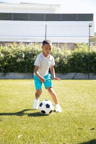 Boy Dribbling Soccer Ball on Sunny Field Active Lifestyle Outdoors
