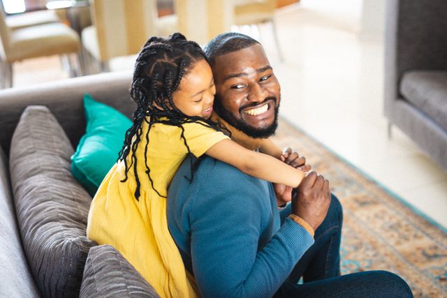 Happy african american father and daughter spending time together in living room at home. unaltered, enjoyment, family, lifestyle and togetherness.