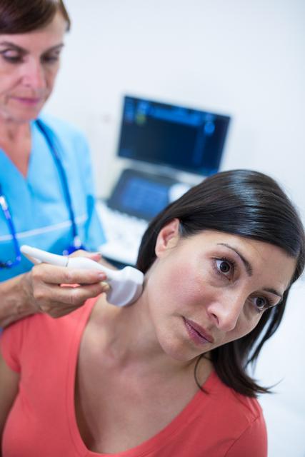 Woman undergoing thyroid ultrasound examination by a healthcare professional in a hospital. Useful for illustrating medical procedures, healthcare diagnostics, patient care, and clinical settings.