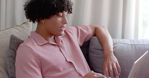 Man Engaged with Laptop on Sofa Showing Casual Relaxation