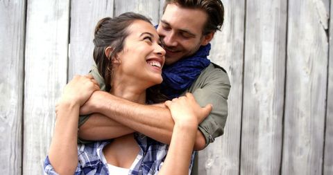 Joyful Young Couple Embracing Against Wooden Background