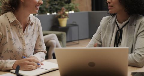 Professional Women Collaborating with Laptop in Modern Office