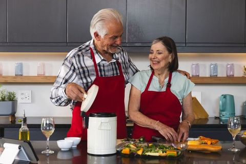 Senior Couple joyfully prepares meals together in kitchen