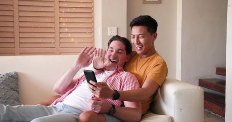Happy Diverse Gay Couple Bonding at Home with Smartphone