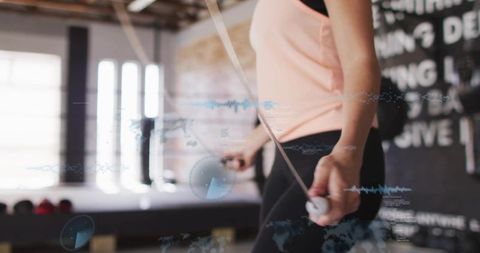 Woman skipping rope in gym wearing peach top and black leggings for dynamic cardio workout