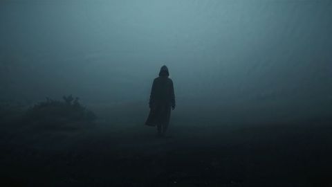 Mysterious Hooded Figure Walking Through Foggy Wilderness