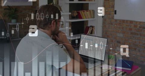 Man analyzing financial data on laptop in home office with brick wall and notebooks