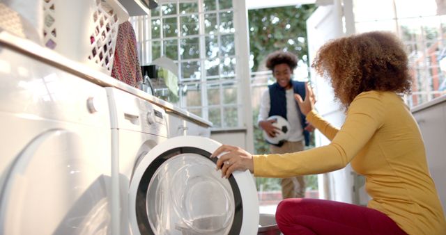 Mother Doing Laundry While Child Enters with Clothes - Download Free Stock Images Pikwizard.com