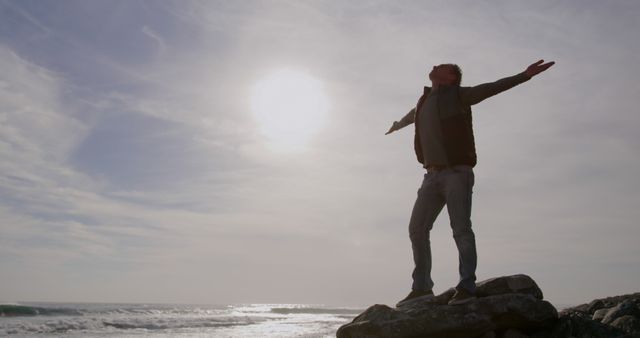 Man Embracing Sunlight with Open Arms on Ocean Cliff Edge - Download Free Stock Images Pikwizard.com