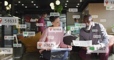 Coworkers collaborating on documents in modern lounge with floating analytics overlays and monitors