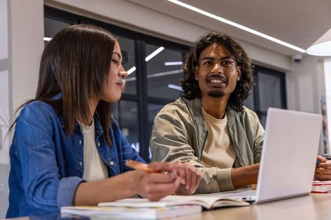 Young asian woman and indian man collaborating and studying at modern coworking table