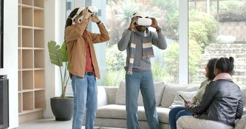 Diverse friends experiencing virtual reality demo in bright light-filled modern living room