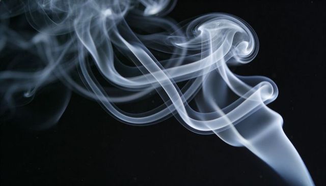 Swirling white smoke ribbons rising and weaving into curving tendrils on black