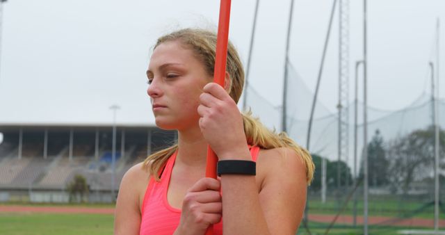 Front view of Caucasian female athlete standing with javelin stick at sports venue. She is standing at sports venue 4k