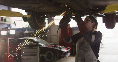 Female Mechanic Using Grinder Underneath Car in Workshop - Download Free Stock Images Pikwizard.com