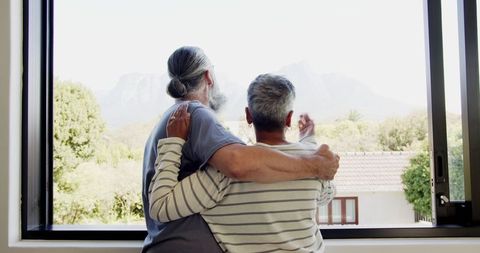 Senior Couple Embracing by Window with Scenic Mountain View