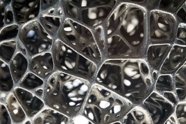 Close-up of metal latticework exhibiting intricate and interwoven patterns, showing detailed textures and geometric structures. Ideal for use in industrial design projects, architectural presentations, modern art exhibits, science and technology presentations, educational materials, and background elements in graphic design.