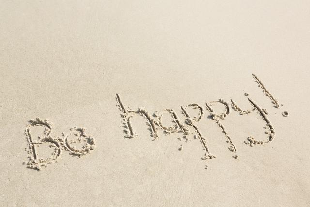 Message 'Be happy!' written in sand on beach, conveying positivity and motivation. Ideal for use in inspirational content, travel promotions, wellness blogs, and social media posts.