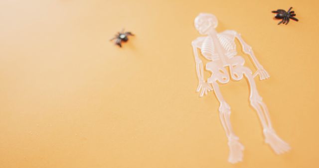 Multiple skeleton and spider toys with copy space against orange background. halloween festivity and celebration concept