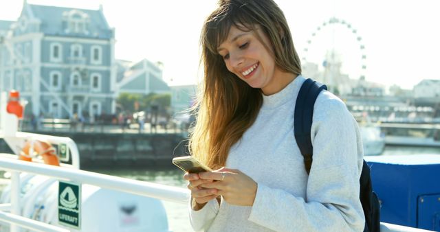 Young Woman Smiling While Texting on Waterfront - Download Free Stock Images Pikwizard.com