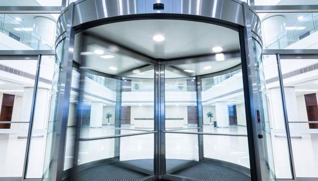 Modern revolving glass door in office lobby with stainless steel accents and polished finish
