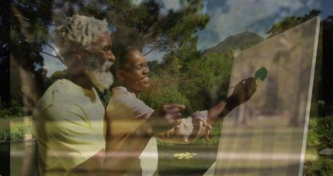 Mature artists enjoying tranquil outdoor painting by pond