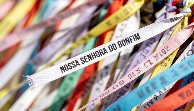 Fluttering colorful prayer ribbons honoring nossa senhora do bonfim on fence