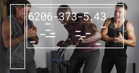 Man powering through assault bike while teammates cheering during intense endurance training