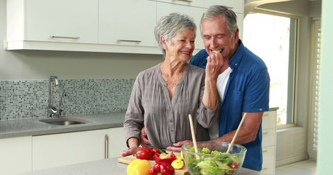 Happy Senior Couple Preparing Salad Together in Modern Kitchen