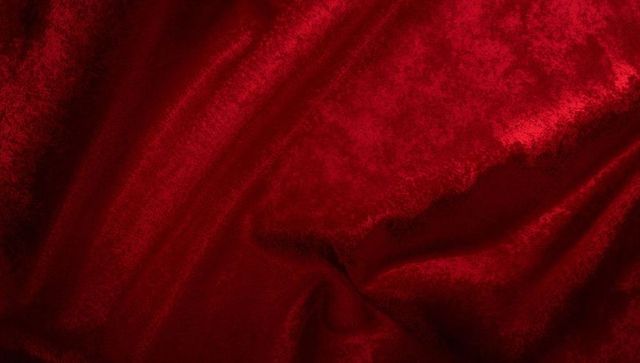 Deep crimson velvet fabric showing rich texture, soft luster and elegant draping