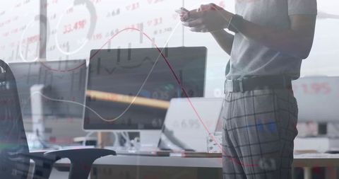 Data analyst reviewing charts on monitors in modern office