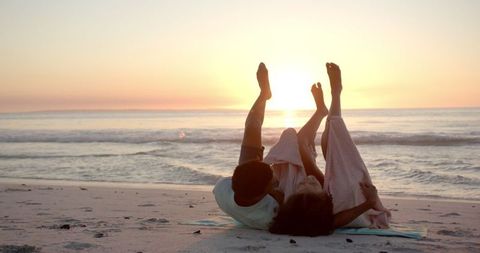Couple Relaxing on Beach at Sunset with Playful Mood