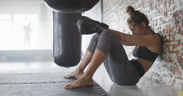 Image of fit and tired caucasian woman relaxing after boxing training at gym. active, fit, sporty and healthy lifestyle, exercising at gym concept.