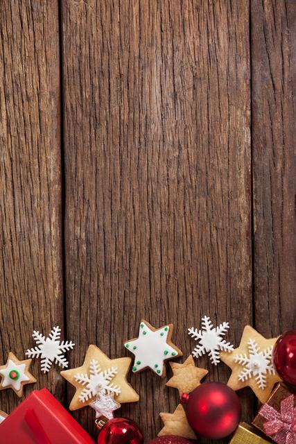 Festive scene with decorated star-shaped cookies and Christmas ornaments on rustic wooden table. Perfect for holiday-themed advertisements, greeting cards, or social media posts. Highlights warmth and tradition associated with Christmas celebrations.