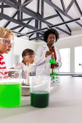 Teaching hands-on stem chemistry as instructor guides children through green-liquid experiment