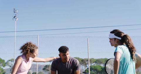 Diverse friends stretching and practicing tennis on sunny outdoor court