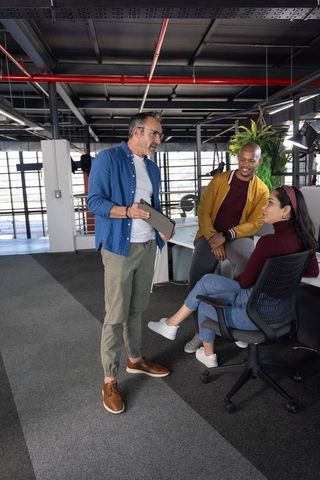 Diverse team collaborating in modern open-plan workspace with tablet and casual style
