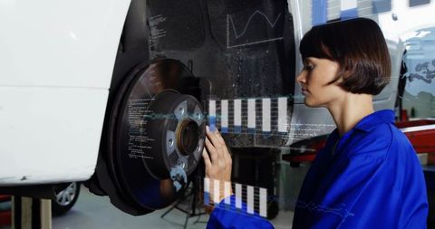 Female mechanic inspecting brake rotor with digital diagnostics overlay