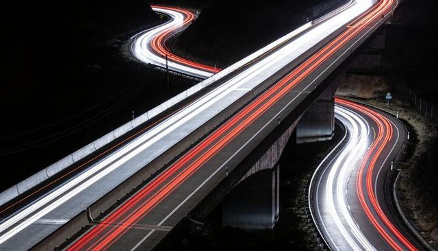 Long exposure light trails on elevated highway and winding road at night
