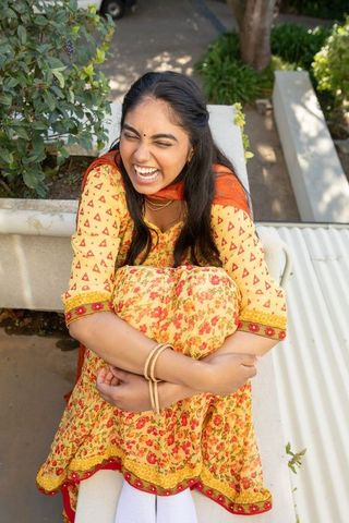 Smiling Indian Woman in Floral Outfit Embracing Joy on Sunny Terrace