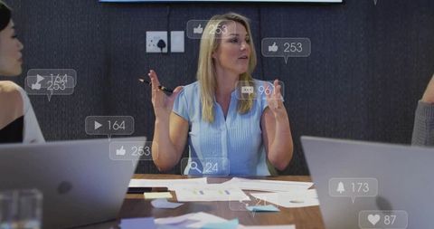 Presenting team leader gesturing during social media marketing meeting with laptops, charts