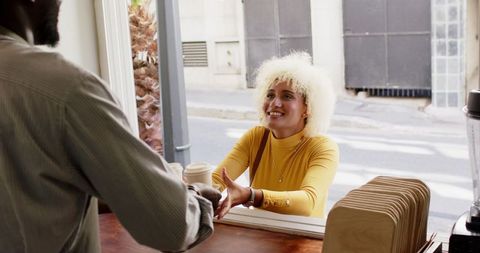 Friendly Exchange: Barista Serving Coffee to Smiling Customer