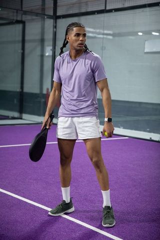 African american athlete standing on purple court holding paddle and ball for pickleball