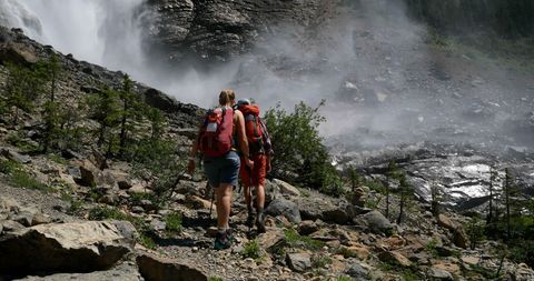 Couple Hiking by Mountain Waterfall in Sunlit Forest - Download Free Stock Images Pikwizard.com