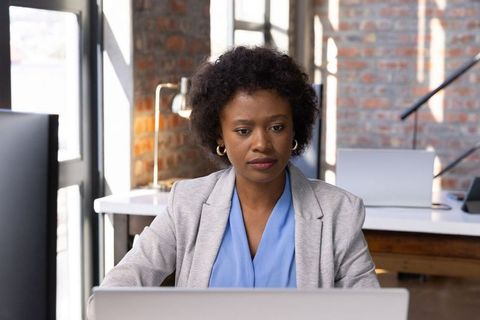African American Businesswoman Typing on Laptop in Industrial Office