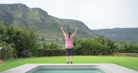 Woman stretching at pool edge with mountain ridge backdrop for backyard wellness routine